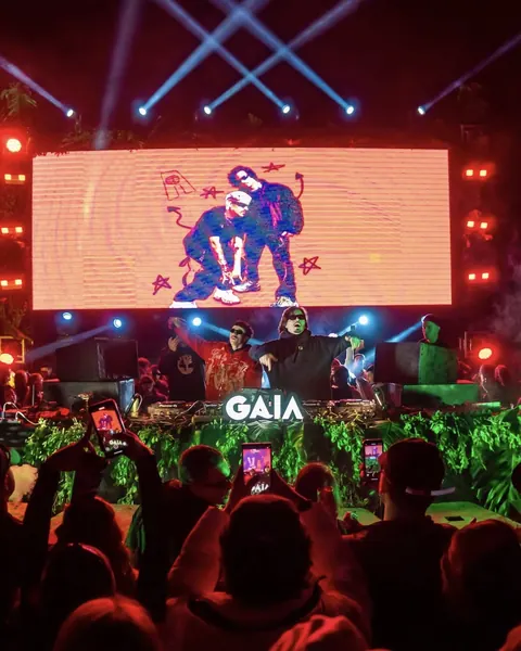 DJs no palco com painel de LED, lasers e o público à frente