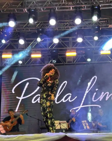 Cantora no palco com painel de LED e treliça de luz